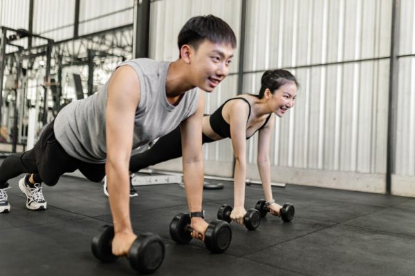 female-male-members-gym-doing-basic-renegade-row-posture-with-dumbbells